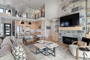 Living area featuring light wood-type flooring, a high ceiling, a fireplace, and recessed lighting