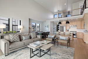 Living area with light wood finished floors, a towering ceiling, and recessed lighting