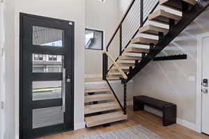 Entryway featuring light wood finished floors, stairs, and a towering ceiling