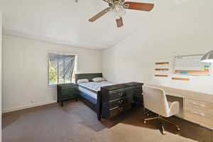 Carpeted bedroom featuring lofted ceiling, a ceiling fan, and an office area
