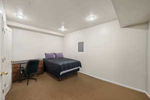 Carpeted bedroom with a desk and electric panel