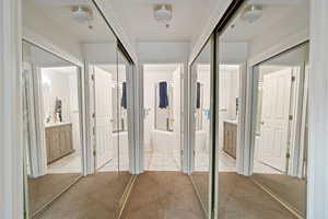 Hall featuring light tile patterned floors and light colored carpet