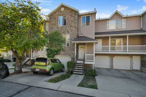 Traditional-style house featuring driveway, a garage, stone siding, and a porch