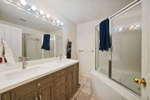 Full bathroom featuring light tile patterned flooring, double vanity, and tiled shower / bath combo