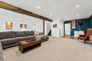 Living area featuring recessed lighting, wet bar, beam ceiling, light carpet, and stairway
