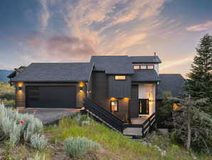 Modern home with roof with shingles, a garage, and driveway