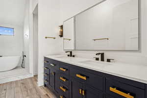 Bathroom with double vanity, a freestanding bath, and light wood-style floors