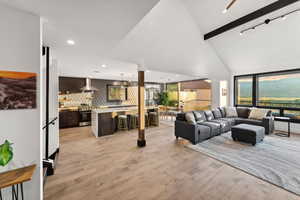 Living room featuring high vaulted ceiling, light wood-style flooring, and beam ceiling