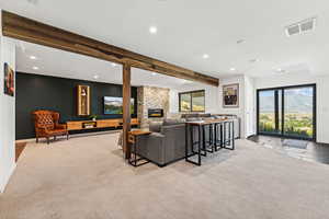 Living room featuring beamed ceiling, recessed lighting, a fireplace, and light colored carpet