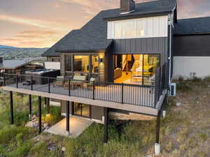 Rear view of property featuring roof with shingles, board and batten siding, and a wooden deck