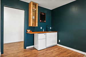 Bar area with white cabinets, wood counters, freestanding refrigerator, and light wood-type flooring