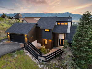 Modern home with roof with shingles, asphalt driveway, an attached garage, board and batten siding, and a deck with mountain view
