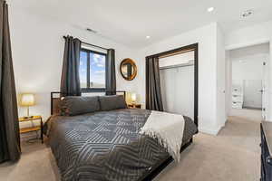 Bedroom featuring light carpet, recessed lighting, and a closet