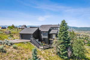 View of front of home featuring a shingled roof, board and batten siding, a mountain view, driveway, and a garage