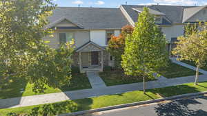 View of front facade with a shingled roof, stone siding, and a front yard