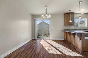 Kitchen featuring dark countertops, brown cabinets, dark wood-type flooring, and healthy amount of natural light