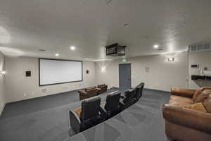 Carpeted home theater featuring a textured ceiling and recessed lighting