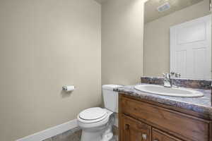 Half bath with vanity and dark stone finish floors