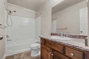 Full bath featuring vanity, shower / bath combination, a textured ceiling, and dark tile patterned flooring