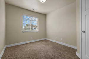 Carpeted spare room featuring baseboards and a textured ceiling
