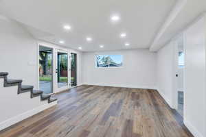 Basement living room with recessed lighting, stairs, dark wood finished floors, and french doors