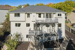 Back of house with a wooden deck, stairway, and a shingled roof