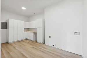 Laundry area with a desk, electric dryer hookup, light wood-style flooring, electric panel, and washer hookup