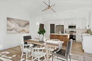 Dining space featuring light wood-style floors, lofted ceiling, and recessed lighting