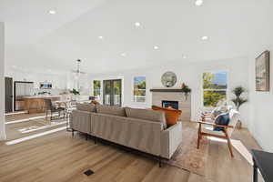 Living area with recessed lighting, light wood-type flooring, lofted ceiling, and a fireplace