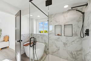 Bathroom with a marble finish shower, recessed lighting, and a soaking tub