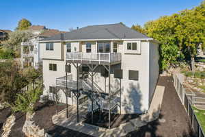 Back of house with a wooden deck, stairway, and a patio