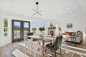 Dining space featuring light wood-style floors, lofted ceiling, a tiled fireplace, recessed lighting, and a chandelier
