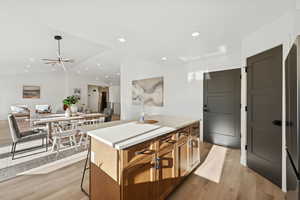 Kitchen featuring light wood-style floors, light countertops, brown cabinets, vaulted ceiling, and a kitchen island