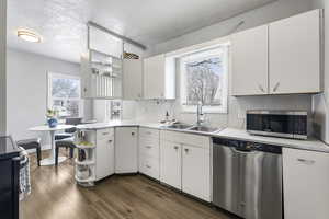 Kitchen with open shelves, stainless steel appliances, light countertops, a peninsula, and white cabinetry