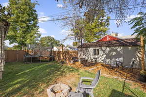 Fenced backyard featuring an outdoor fire pit and a trampoline