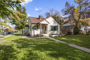Bungalow featuring a front lawn, a chimney, and roof with shingles