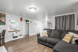 Living room featuring heating unit, a textured ceiling, and light wood-style floors