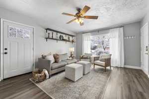 Living area featuring a ceiling fan, wood finished floors, and a textured ceiling