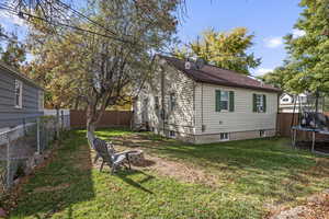 View of property exterior with a fenced backyard, a trampoline, and an outdoor fire pit