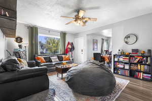 Living area with a textured ceiling, wood finished floors, and a ceiling fan