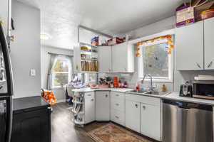Kitchen featuring open shelves, black appliances, dark wood finished floors, light countertops, and a textured ceiling