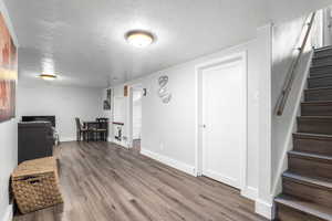 Finished basement featuring stairway, a textured ceiling, and wood finished floors