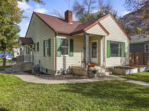 View of front of house featuring a chimney and a shingled roof