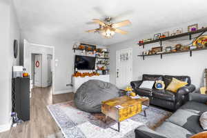 Living room with light wood finished floors, a ceiling fan, and a textured ceiling