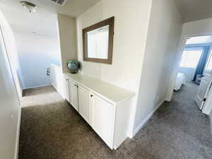 Hall with dark colored carpet, an upstairs landing, and a textured ceiling