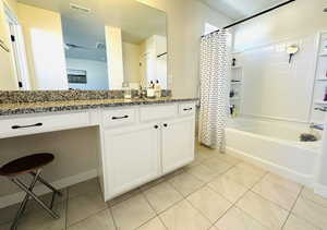 Bathroom featuring vanity, light tile patterned flooring, and shower / bath combo with shower curtain