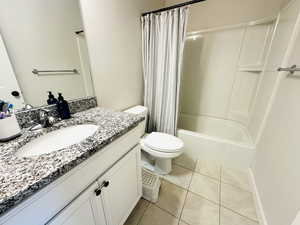 Full bathroom featuring shower / bath combination with curtain, vanity, and light tile patterned floors