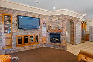 Living room featuring a fireplace, ornamental molding, light wood-type flooring, and recessed lighting