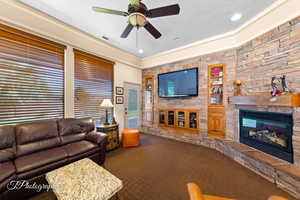Living room featuring dark carpet, a fireplace, built in shelves, a ceiling fan, and recessed lighting