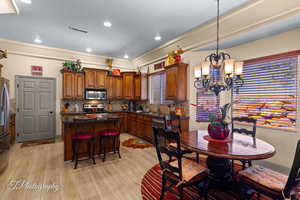 Kitchen featuring a chandelier, backsplash, hanging light fixtures, dark stone counters, and a breakfast bar area